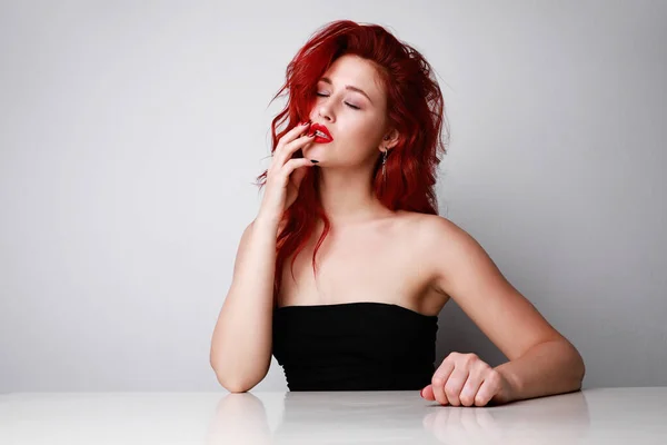 Femme sensuelle et séduisante avec les yeux fermés et de beaux cheveux longs rouges posant sur fond blanc. Espace pour le texte. Images De Stock Libres De Droits