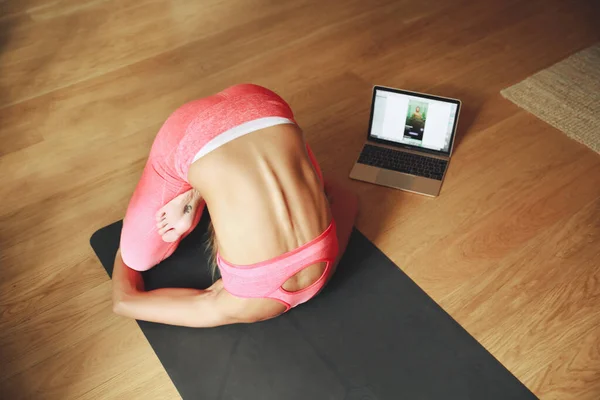 Žena dělá ranní jógu doma, pomocí notebooku cor jóga on-line. — Stock fotografie