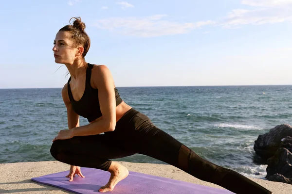 Testa di donna, facendo yoga asana in spiaggia con gli occhi chiusi, indossando vestiti sportivi con sfondo sfocato. — Foto Stock