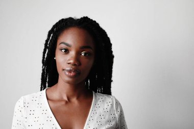 Mutlu bir gülümsemeyle stüdyoda poz veren neşeli, kıvırcık saçlı genç siyahi kadının yakın çekimi.. 