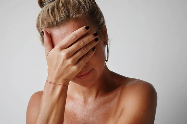 Retrato de una hermosa chica con el pelo rubio frunciendo el ceño con desagrado. Atractiva joven en postura cerrada. — Foto de Stock