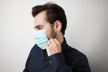 Tıbbî maske takan genç adam kendini izolasyon Coronavirus 'tan koruyor..