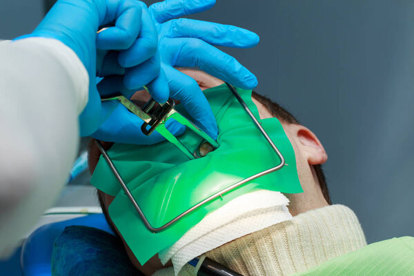 Дантист очень тщательно проверяет и восстанавливает зуб своего молодого пациента
