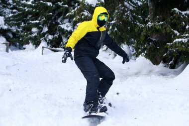 Dağ yamacında bir sarı ceketli Snowboarder