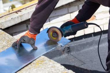 İşçi, çim biçme makinesi kullanarak metal keser.