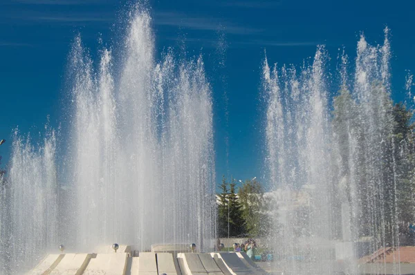 Fontäne mit Wasserstrahlen und Spritzern gegen den blauen Himmel — Stockfoto