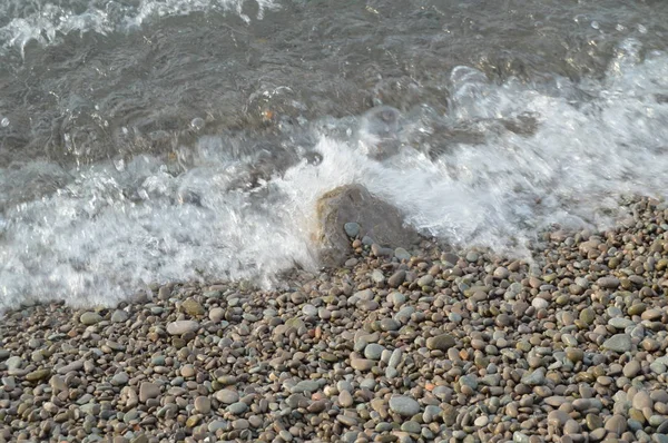 小石のビーチ、水、泡、背景の海岸に海の波 — ストック写真