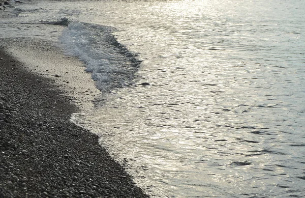 海の小石のビーチ、早朝日の出に光沢のある銀水 — ストック写真