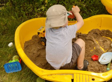 Küçük çocuk bir güneşli yaz gününde bir kum renkli plastik oyuncakları ile oynarken