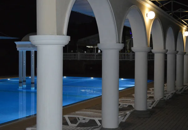 Vista nocturna de la lujosa piscina con columnas y arcos, reflejada en el agua — Foto de Stock