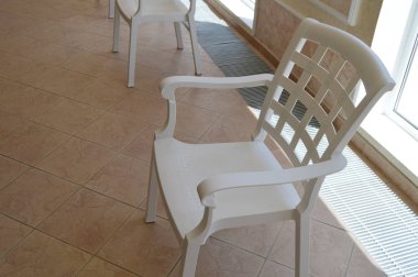 Beyaz plastik sandalye Havuzu Oda pencere, oturma alanı yakınında duruyor