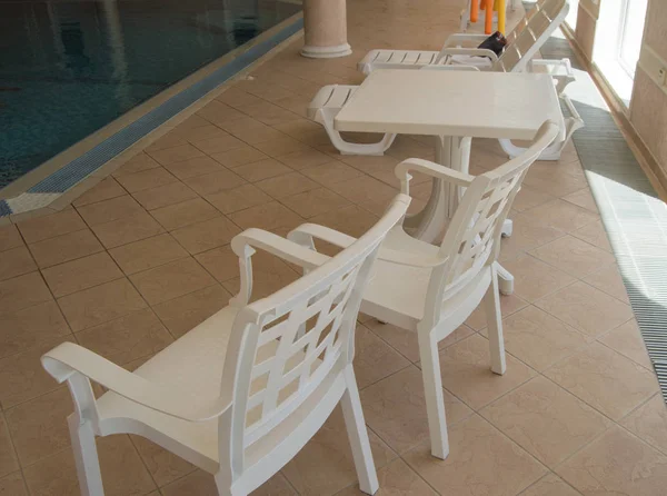 Rekreasyon alanı kapalı havuzun yanında beyaz plastik sandalyeler bulunmaktadır