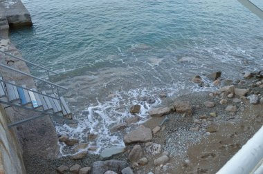 Metal bir merdiven deniz rıhtıma, kayalar dalgalar kazası.