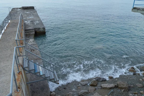 Metal bir merdiven deniz rıhtıma, kayalar dalgalar kazası.