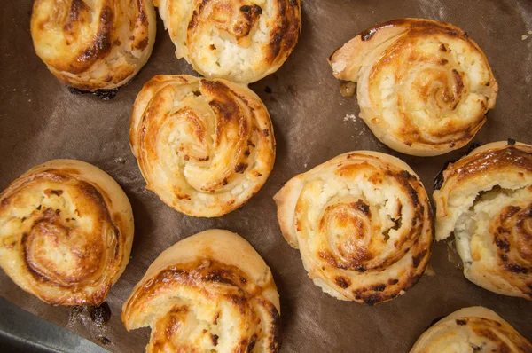 Fresh sweet homemade buns twisted in rolls on parchment paper. Top view — Stock Photo, Image
