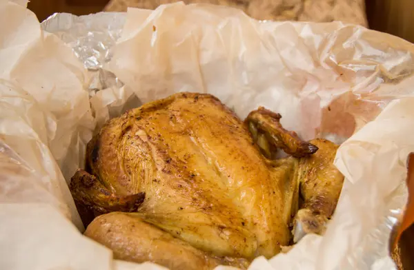 Pollo entero a la parrilla con piel dorada crujiente en pergamino blanco, vista superior, primer plano — Foto de Stock