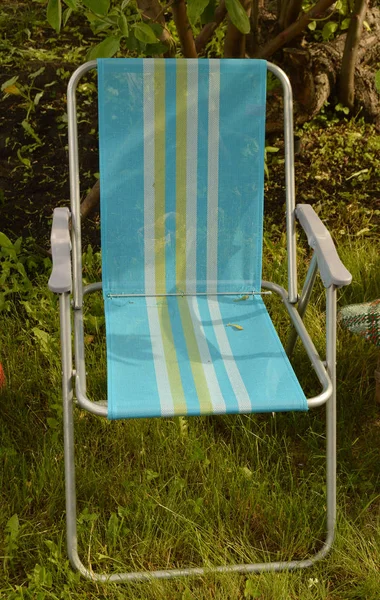 Cadeira de acampamento está situado no jardim na grama — Fotografia de Stock