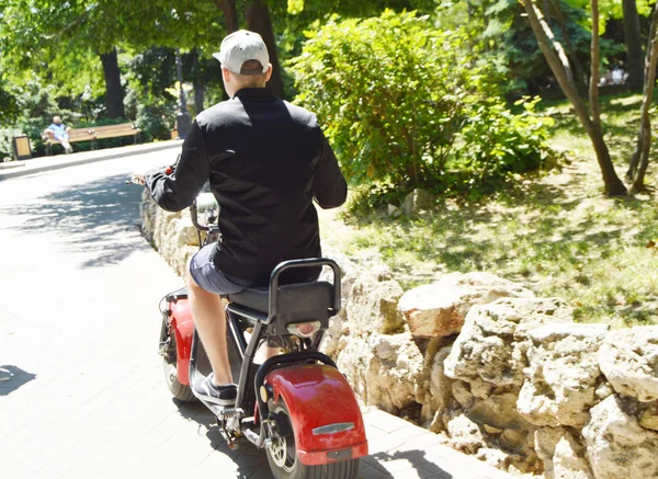 Αναβάτης σε ένα σκούτερ στην πόλη σε μια ηλιόλουστη ημέρα στο πάρκο — Φωτογραφία Αρχείου