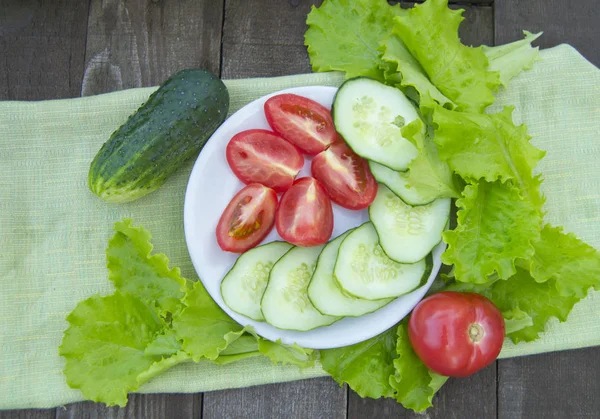 Gurkenscheiben und Tomaten mit Salat auf altem Holztisch — Stockfoto