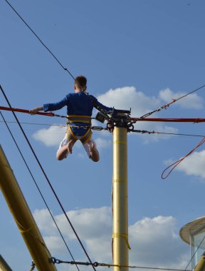 Çocuk memnuniyetle mavi gökyüzüne karşı eğlence parkı bungee atlar