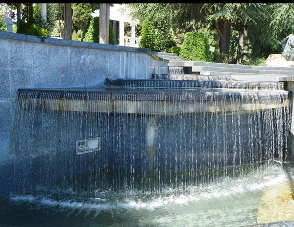 Mesterséges vízesés vízzel fúvókák, kő modern szerkezet, gyönyörű art design a parkban — Stock Fotó
