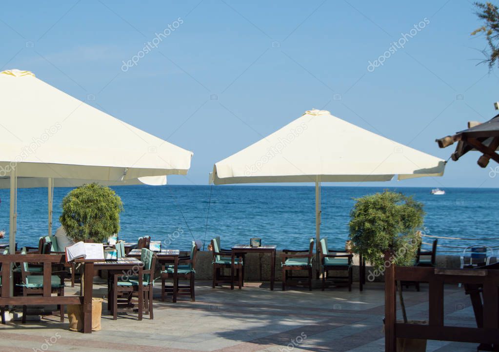 Tables and umbrellas at the seaside restaurant on a Sunny summer day