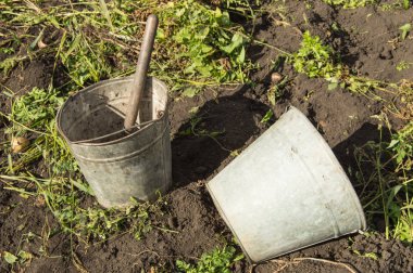 İki eski kirli paslı demir kovalar arka bahçede çim ve toprak yakın çekim