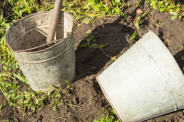 Detail dva staré špinavé zrezivělého kbelíky na pozadí půdy a tráva v zahradě — Stock fotografie