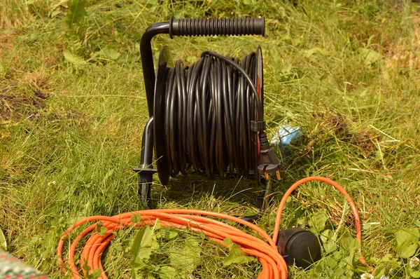 Rulo çim elektrik kablo ve uzatma kablosu, bahçede inşaat işleri için elektrikli araçları ile — Stok fotoğraf