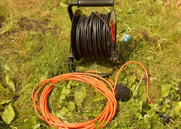 Rulo çim elektrik kablo ve uzatma kablosu, bahçede inşaat işleri için elektrikli araçları ile — Stok fotoğraf