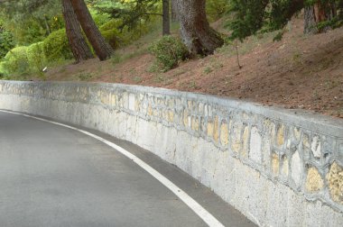 Asfalt yol taş duvar ve servi ağaçları çalışır