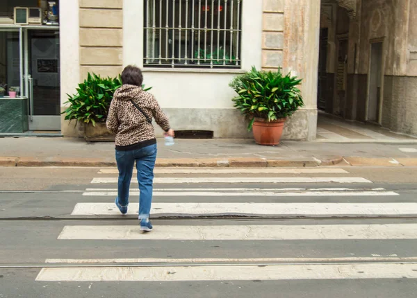 Жінка туристів в Мілані швидко перетинає дорога на пішохідному переході, вигляд зі спини — стокове фото