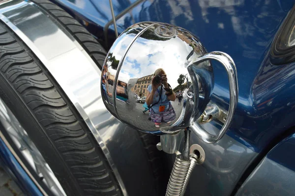 Drôle le reflet d'une femme photographe dans le phare chromé de la vieille voiture, le concept de tourisme et de photographie — Photo