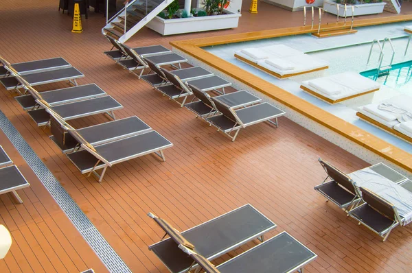 Вид зверху на розкішний басейн з порожніми сонячними ліжками на відкритій палубі сучасного круїзного лайнера — стокове фото