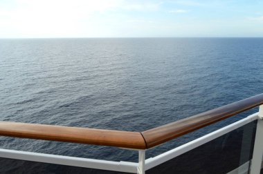 Modern bir yolcu gemisinin açık güvertesinden deniz manzarası, parmaklıklar ve güçlü cam duvarlar..
