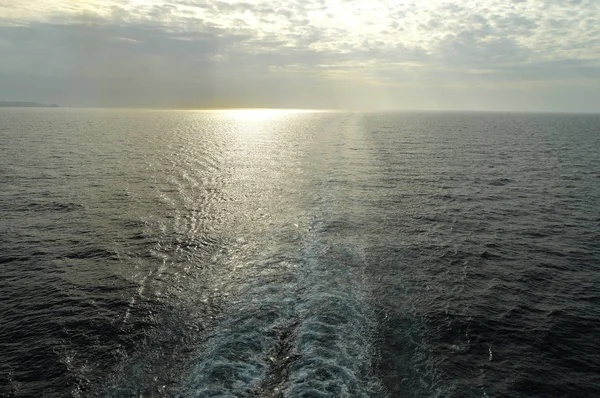Vestígios de ondas e espuma na superfície do mar azul com uma cópia do espaço ao pôr do sol — Fotografia de Stock