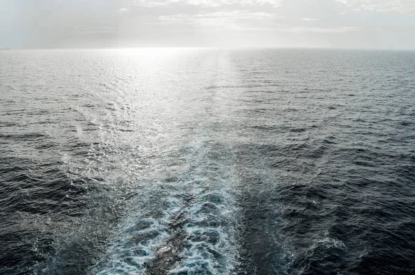 Traces de vagues et de mousse à la surface de la mer bleue avec une copie de l'espace au coucher du soleil — Photo