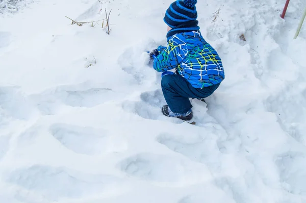 魅力的な赤ちゃん男の子掘削雪の青い小さなシャベルで冬の日 — ストック写真
