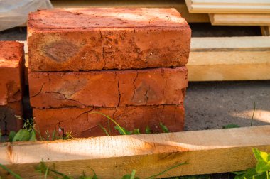 Bahçedeki yeni kırmızı tuğlalar, tahtalar, onarım malzemeleri çimenlerin üzerinde yatıyor..