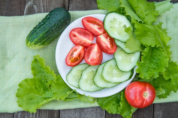 Gurkenscheiben Und Tomaten Liegen Auf Einem Weißen Teller Daneben Salat — Stockfoto