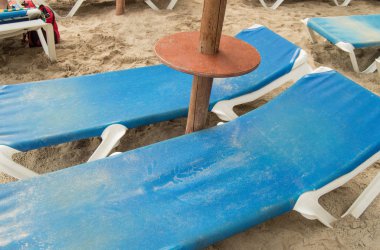 Palma de Mallorca 'nın kumlu kumsalında şezlonglar ve saman şemsiyeler.