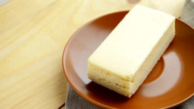 Kadın el koyar bir tabak bir klasik new York cheesecake ile hafif bir ahşap arka plan ve peçeteler