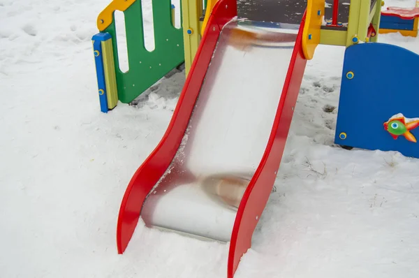 雪に覆われた遊び場 白い雪の背景の小さな子供のための空の金属スライド — ストック写真