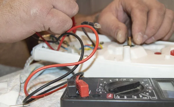 Close-up of the old electricians hand, the use of digital voltmeter for voltage to repair the electric iron, selective focus — Stock Photo, Image