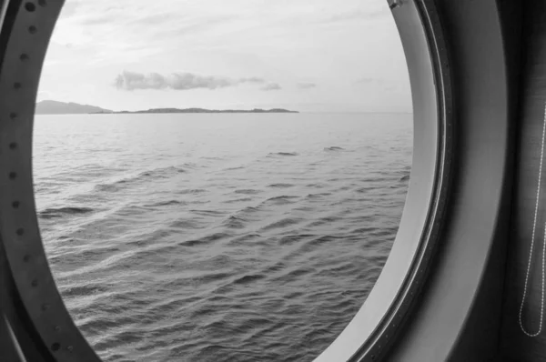 Round porthole on a cruise ship, interior view through the window on the coast and the sea, sunrise against the sea, close-up — Stock Photo, Image