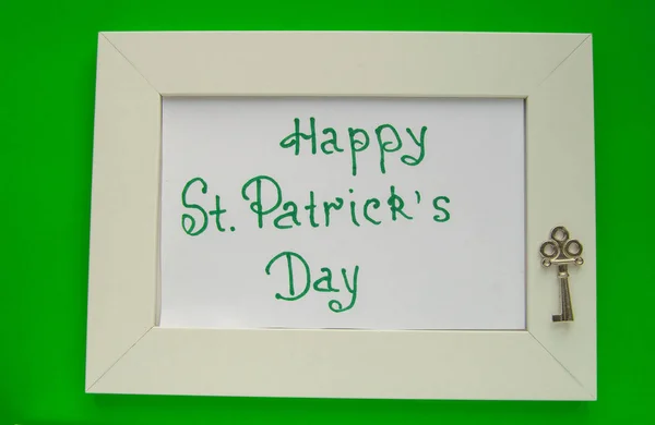 St. Patricks day greeting card with white frame on green background, key to wealth and treasures
