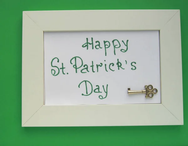 St. Patricks day greeting card with white frame on green background, key to wealth and treasures