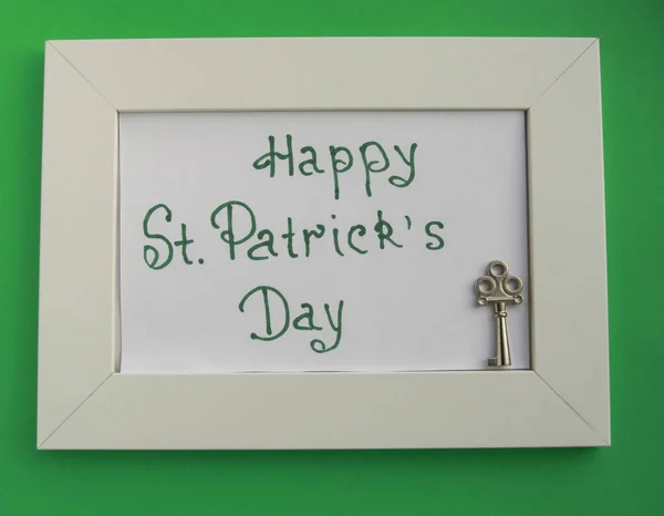 St. Patrick\'s day greeting card with white frame on green background, key to wealth and treasures.