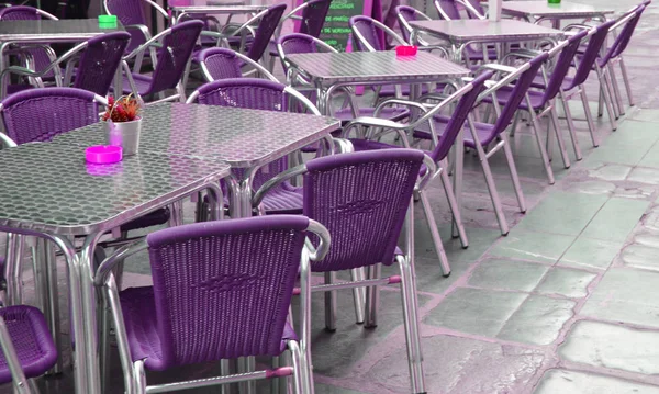 Empty European street cafe with purple chairs and tables, selective focus.