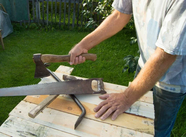 Muž drží sekeru, pracuje se stavebními nástroji ve své zahradě — Stock fotografie